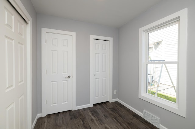 unfurnished bedroom with dark wood-type flooring and baseboards