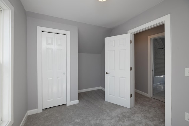 unfurnished bedroom with carpet, lofted ceiling, a closet, and baseboards