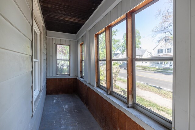unfurnished sunroom with wooden ceiling and wooden walls