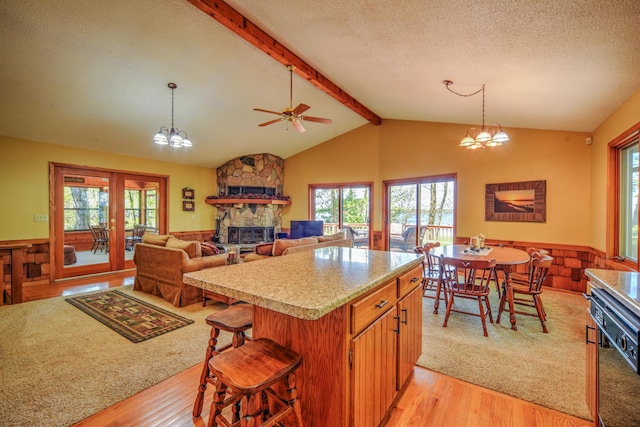 27166 Hersant Rd, Meenon Twp, WI 54893 - kitchen with light wood finished floors, a wainscoted wall, light countertops, a stone fireplace, and pendant lighting