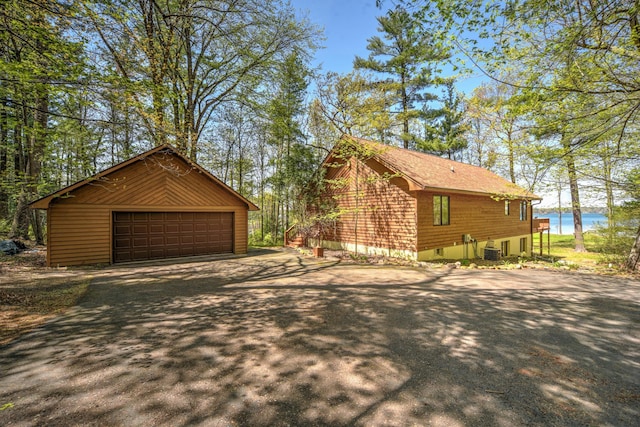 27166 Hersant Rd, Meenon Twp, WI 54893 - view of property exterior with central AC unit, an outbuilding, a garage, and a water view