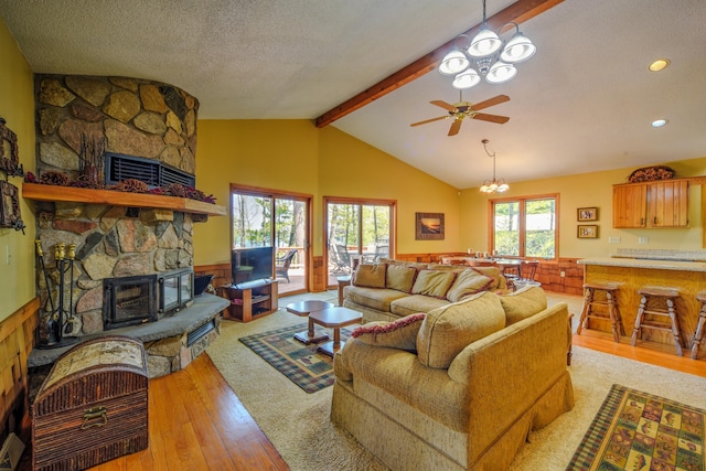 27166 Hersant Rd, Meenon Twp, WI 54893 - living room featuring a stone fireplace, light wood-type flooring, a chandelier, a wainscoted wall, and a textured ceiling