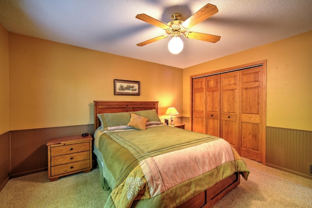 27166 Hersant Rd, Meenon Twp, WI 54893 - bedroom featuring wainscoting, carpet floors, a closet, wood walls, and a ceiling fan