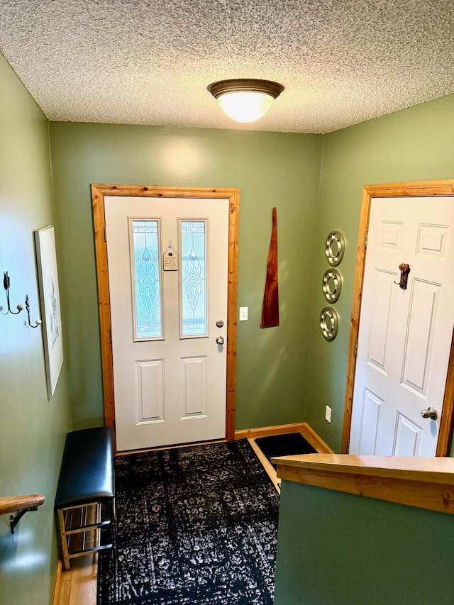 foyer entrance featuring a textured ceiling and baseboards