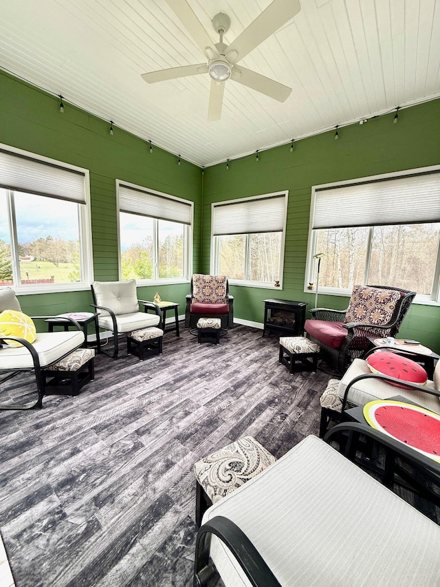sunroom featuring wood finished floors, ceiling fan, an outdoor living space, a deck, and wooden ceiling