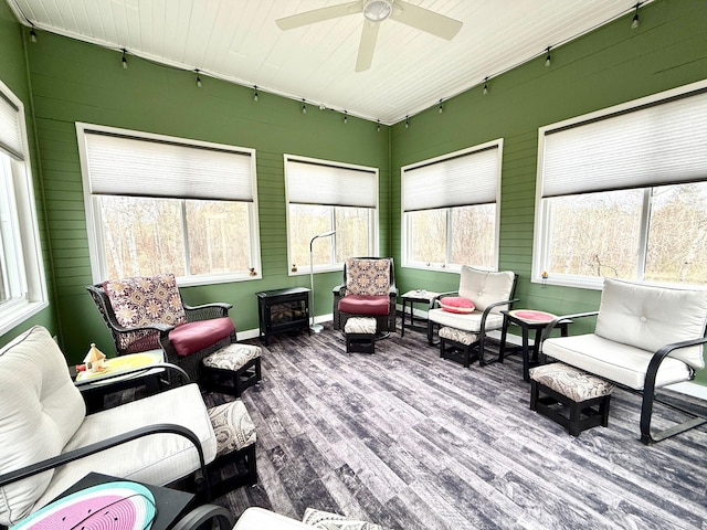 sunroom / solarium featuring an outdoor living space, ceiling fan, wood finished floors, and rail lighting