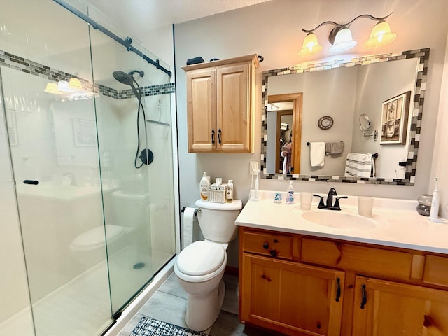 bathroom featuring a shower stall, toilet, and vanity