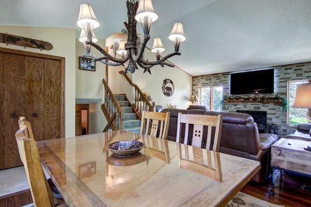 14177 205th St N, Scandia, MN 55073 - dining space with stairs, a fireplace, wood finished floors, vaulted ceiling, and a chandelier