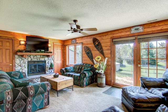 14177 205th St N, Scandia, MN 55073 - living room featuring a textured ceiling, ceiling fan, wood walls, a fireplace, and carpet