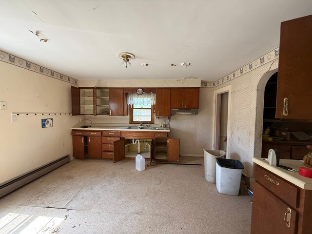 408 Jefferson St, Minneota, MN 56264 - kitchen featuring a baseboard radiator, light countertops, arched walkways, under cabinet range hood, and a sink