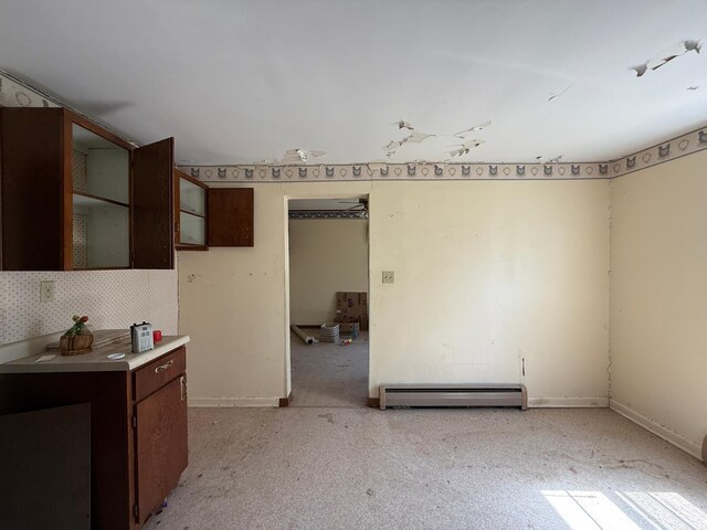 408 Jefferson St, Minneota, MN 56264 - kitchen with a baseboard heating unit, dark brown cabinets, glass insert cabinets, light colored carpet, and light countertops