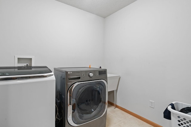 clothes washing area featuring separate washer and dryer, baseboards, and a textured ceiling