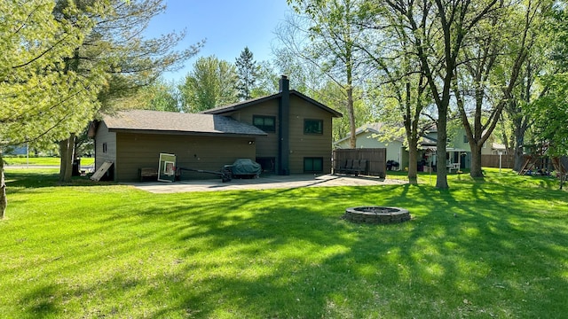 rear view of property featuring a patio, a fire pit, and roof with shingles