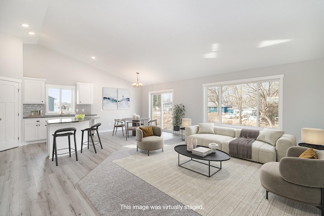 living area featuring a chandelier, light wood-style floors, recessed lighting, and high vaulted ceiling