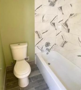 bathroom featuring toilet and a tub to relax in
