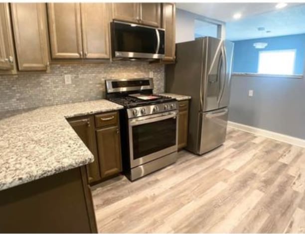 kitchen with stainless steel appliances, backsplash, light wood-type flooring, recessed lighting, and light stone counters