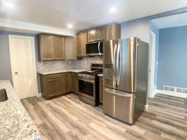 kitchen with stainless steel appliances, light wood-style flooring, tasteful backsplash, baseboards, and recessed lighting