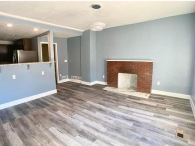 unfurnished living room featuring wood finished floors, baseboards, and a fireplace