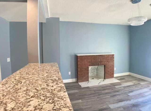 unfurnished living room featuring dark wood-type flooring, baseboards, and a fireplace