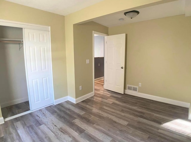 unfurnished bedroom featuring dark wood finished floors, baseboards, and a closet