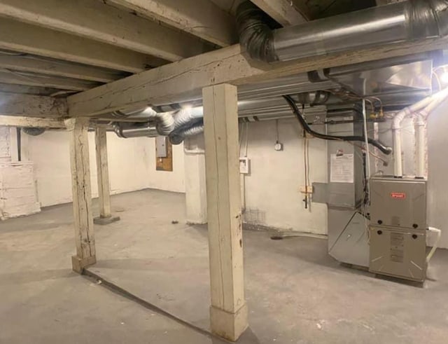 unfinished basement featuring electric panel and heating unit