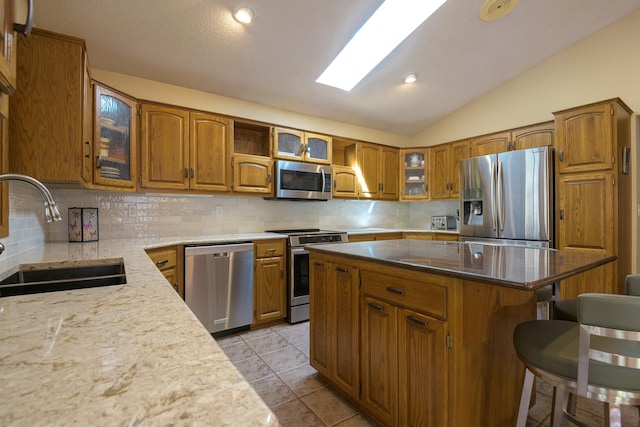 514 10th St N, Sartell, MN 56377 - kitchen with appliances with stainless steel finishes, a sink, brown cabinetry, a breakfast bar area, and tasteful backsplash