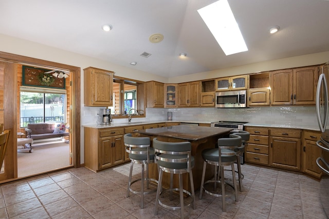 514 10th St N, Sartell, MN 56377 - kitchen with appliances with stainless steel finishes, vaulted ceiling, a sink, healthy amount of natural light, and brown cabinets