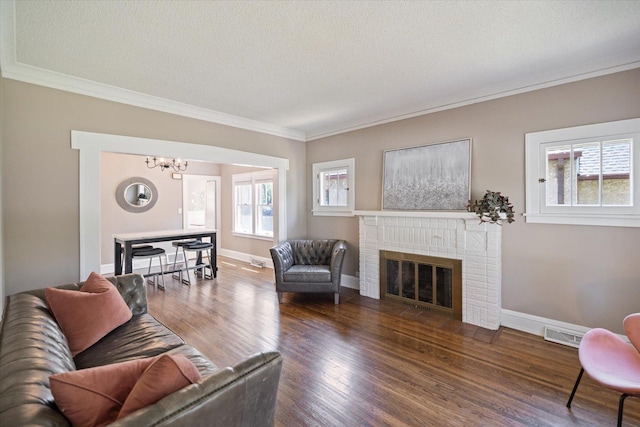 4505 47th Ave S, Minneapolis, MN 55406 - living room with crown molding, a chandelier, a textured ceiling, a brick fireplace, and dark wood-style floors