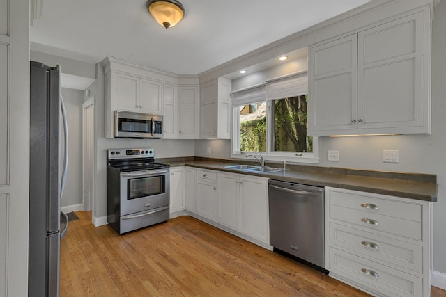 506 Riverside Dr SE, Saint Cloud, MN 56304 - kitchen featuring appliances with stainless steel finishes, a sink, dark countertops, light wood finished floors, and baseboards