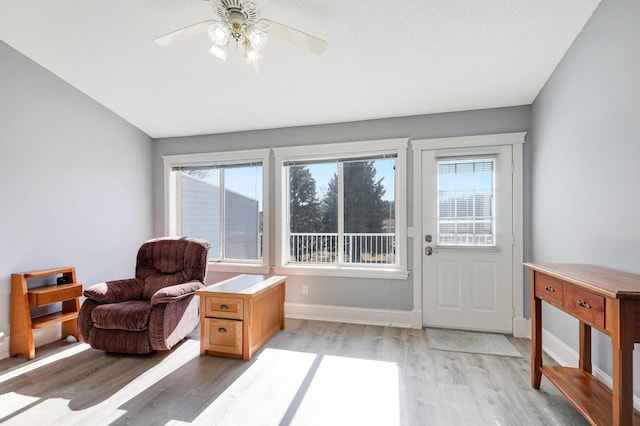 living area with light wood-style flooring, a ceiling fan, and baseboards