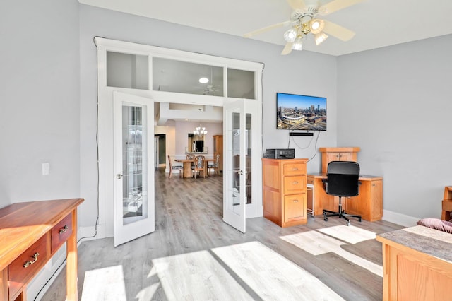 home office featuring french doors, light wood-type flooring, ceiling fan, and a chandelier