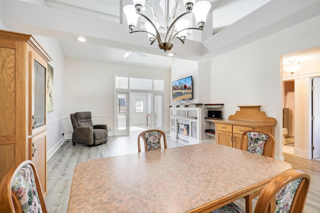 dining space with a glass covered fireplace, light wood finished floors, a chandelier, recessed lighting, and baseboards