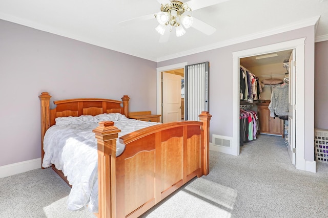 bedroom with light carpet, ornamental molding, a walk in closet, a closet, and baseboards