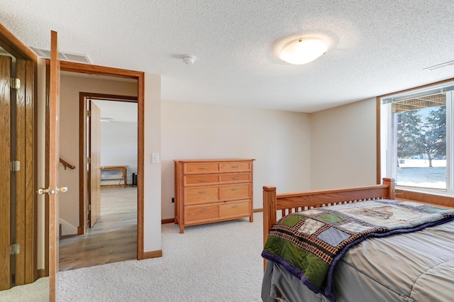 bedroom with light colored carpet and a textured ceiling