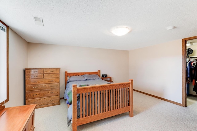 carpeted bedroom featuring a walk in closet, baseboards, a closet, and a textured ceiling