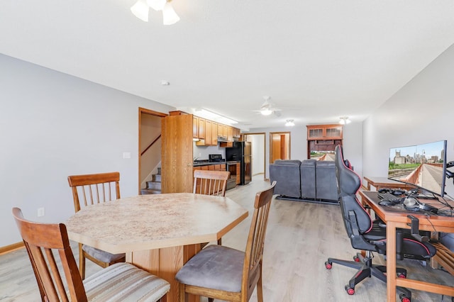 dining room with ceiling fan, light wood finished floors, an office area, and stairway