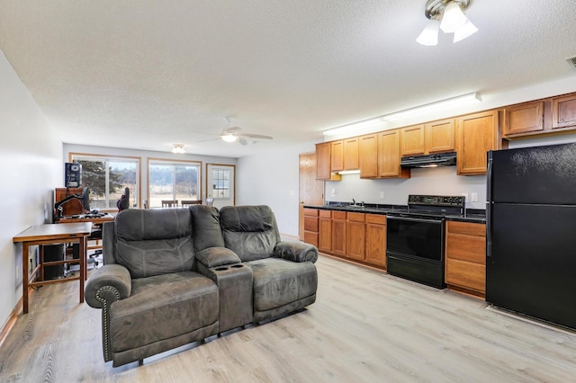 kitchen featuring black appliances, under cabinet range hood, a ceiling fan, open floor plan, and light wood-style flooring