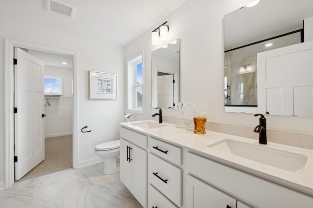 full bath with a walk in shower, toilet, marble look tiles, double vanity, and baseboards