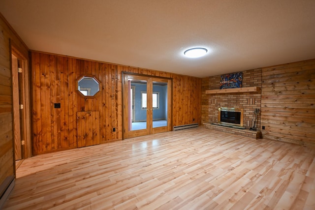 1192 Blackburn Rd, Scott Twp, WI 54801 - unfurnished living room with a baseboard heating unit, wood finished floors, wooden walls, a fireplace, and french doors