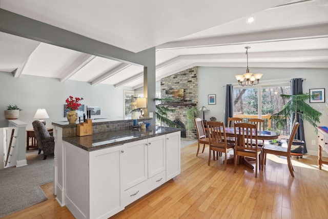 2241 17th St NW, New Brighton, MN 55112 - kitchen with a chandelier, white cabinetry, light wood-type flooring, a fireplace, and decorative light fixtures