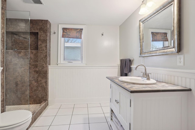 2241 17th St NW, New Brighton, MN 55112 - bathroom with wainscoting, tiled shower, vanity, toilet, and tile patterned flooring