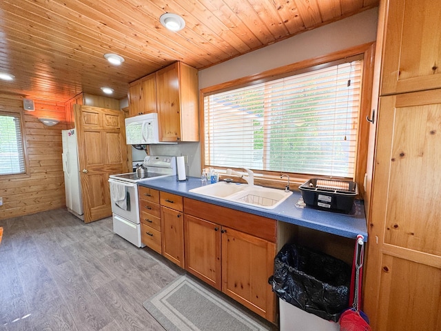 41443 County Highway 1, Ottertail, MN 56571 - kitchen featuring white appliances, a sink, light wood-style floors, dark countertops, and wooden walls