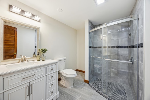 full bathroom with toilet, vanity, a shower stall, and baseboards