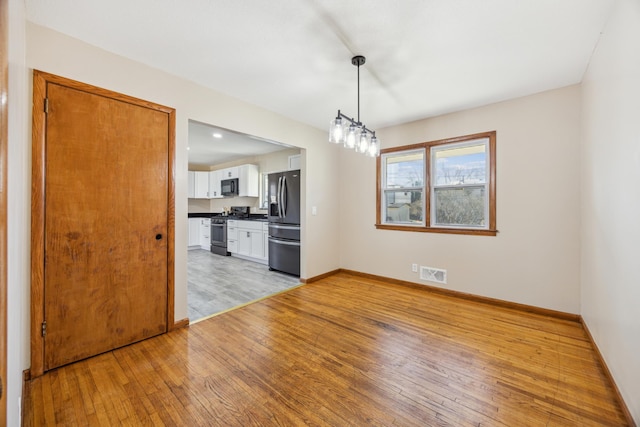 unfurnished dining area with light wood-type flooring and baseboards