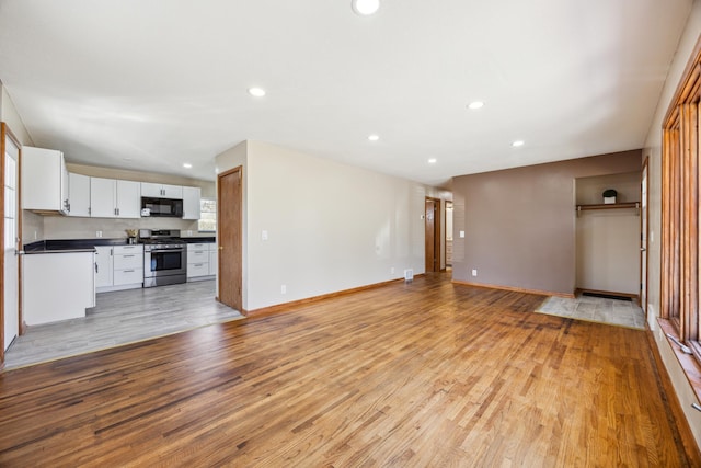 unfurnished living room featuring light wood-type flooring, recessed lighting, and baseboards
