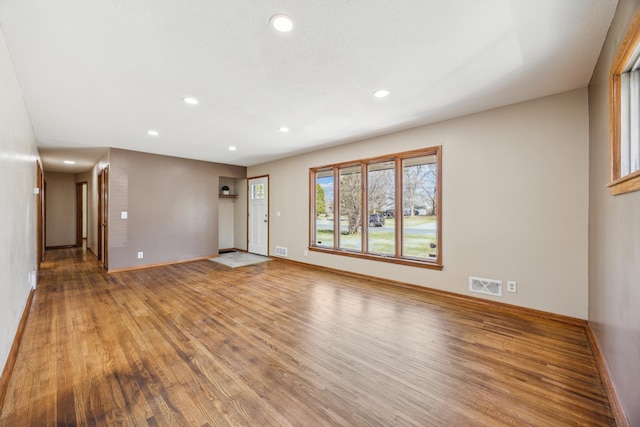 unfurnished living room with wood finished floors, recessed lighting, and baseboards