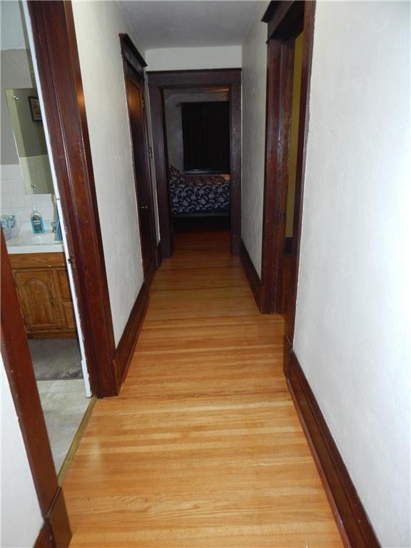 hall with light wood-style floors and baseboards