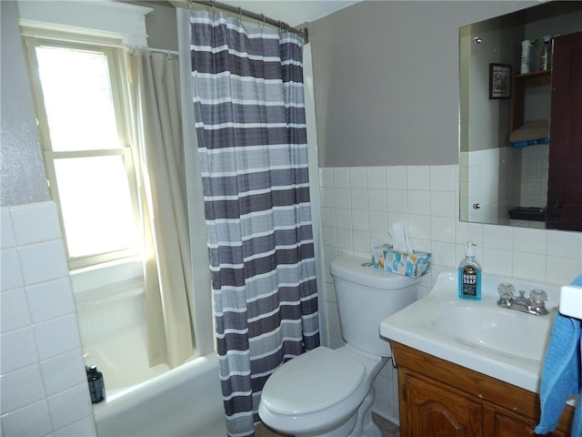 full bathroom with tile walls, toilet, vanity, shower / bath combo, and wainscoting