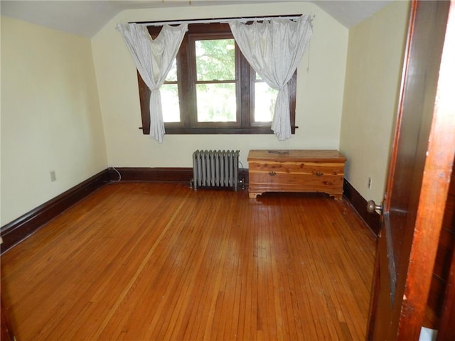 additional living space with radiator heating unit, lofted ceiling, hardwood / wood-style flooring, and baseboards