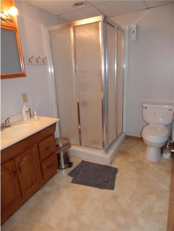 bathroom featuring toilet, a stall shower, and vanity